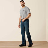 Ariat Rebar M4 Relaxed DuraStretch Edge Boot Cut Jean model wearing grey t-shirt and jeans standing in a well-lit room.
