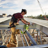 Ariat Rebar M4 DuraStretch work pants worn by a construction worker atop a steel structure, highlighting durability and comfort.