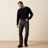 A man wearing Ariat Rebar M4 Low Rise DuraStretch stackable straight leg pants and a black long sleeve shirt.