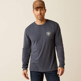 A man wearing an Ariat Saltillo Lockup T-Shirt and a brown cap, standing against a light background.