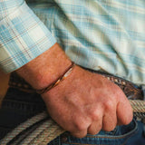 Montana Silversmiths Rustic Solstice Cuff Bracelet worn on a man's wrist while holding a rope.