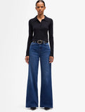 Model wearing 7 For All Mankind ultra high rise wide leg jeans with a black long sleeve top and a stylish belt.