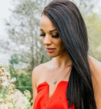 Waves of Love Heart necklace worn by a woman in a red dress, surrounded by nature.