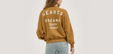 Wrangler® X Lainey Wilson Good Jeans Sweatshirt in brown, featuring a stylish back design with 'HEARTS DREAMS GOOD JEANS' lettering.