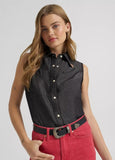Woman wearing Wrangler x Lainey Wilson black denim sleeveless western shirt with pink pants and a belt.