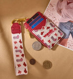 Wrangler Women's Western Print RFID Blocking Wallet in Pink with lanyard and coins on a textured background.