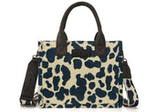 Wrangler Cow Print Concealed Carry Tote with dual handles and crossbody strap, featuring a bold cow pattern.