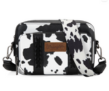 Wrangler cow print crossbody purse with wallet compartment featuring whipstitch detailing and leather logo.
