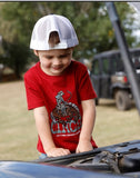 Cinch toddler boy wearing a red short sleeve graphic tee while exploring under the hood of a vehicle.