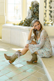 Woman wearing Black Star Cameron - Shiitake Boot with floral dress, sitting in bright room.