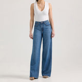 Model wearing Wrangler Retro® Bailey high rise wide leg jeans in blue, paired with a white tank top, showcasing stylish denim.