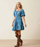 Ariat Women's Juliet Dress in light wash indigo denim with puff sleeves, worn with western boots, perfect for casual outings.