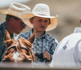 Young boy wearing a Resistol Young Gun Jr. Youth Cowboy Hat, surrounded by cattle and other riders.
