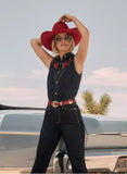 Woman wearing Wrangler Lainey Wilson embroidered sleeveless denim shirt with red hat, showcasing bold summer style.