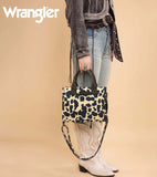Woman holding Wrangler Cow Print Concealed Carry Tote with dual carry options and stylish cowgirl outfit.