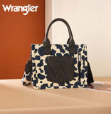 Wrangler Cow Print Concealed Carry Tote & Crossbody Bag in black and cream with handles on a table.