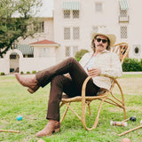 Man wearing Tecovas cowboy boots relaxing in a chair outdoors, showcasing a stylish western look.