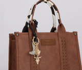Wrangler Western Cowhide Cowboy Boot Bag Charm attached to a stylish brown handbag.