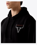 Close-up of a man wearing an Ariat hoodie featuring a bull skull graphic on the chest.