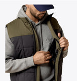 Ariat Men's Crius Insulated Vest in Phantom/Grape Leaf, showcasing a man inspecting the interior pocket.