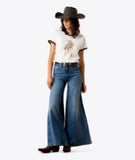 Model wearing Ariat Women's Sundance Short Sleeve T-Shirt with wide-leg jeans and a cowboy hat.