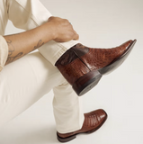 Tecovas cowboy boots featuring a striking caiman belly design in dark pecan, showcased on a model's foot.