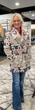 Navajo tie front blanket wrap jacket with hood worn by a smiling woman in a store setting.